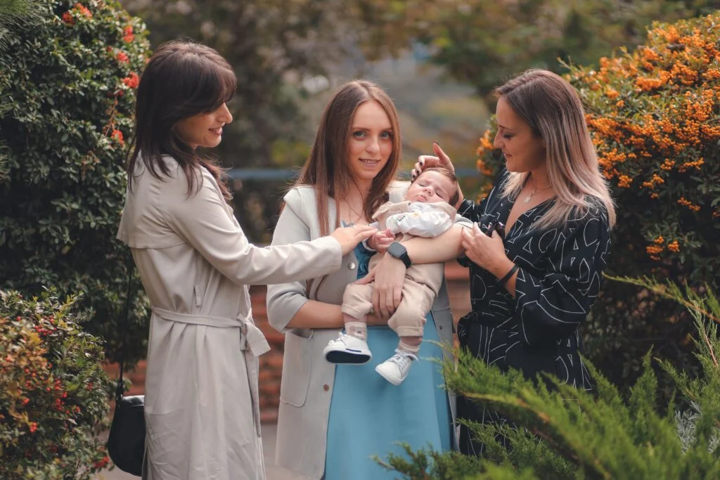 Three moms gathered around a baby outdoors